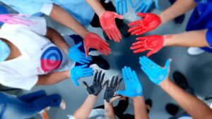 12 mãos com as palmas pintadas de azul, preto ou vermelho formam um circulo