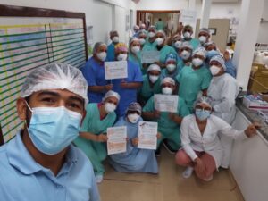 Em primeiro plano há o homem que faz a selfie. Atrás dele estão vários colaboradores segurando cartazes. Uns estão ajoelhados, outros em pé ou agachados.