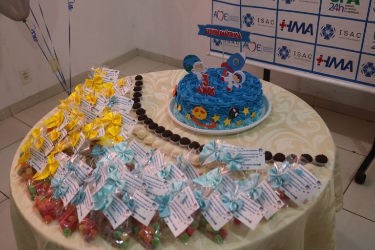 Mesa com bolo de aniversário com cor predominante azul e outros doces.