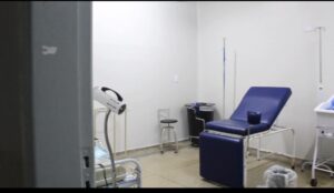 Sala hospitalar com paredes brancas, poltrona azul e lixeira preta
